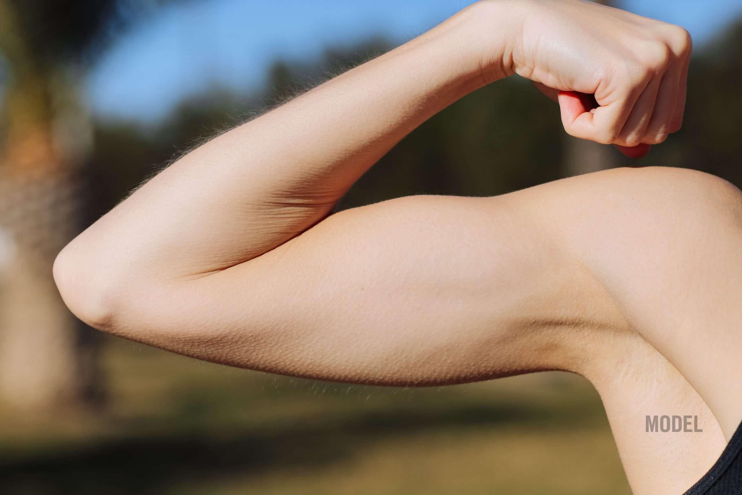 Woman showing toned arm representing loose skin after Ozempic, GLP-1 weight loss, and body contouring after weight loss
