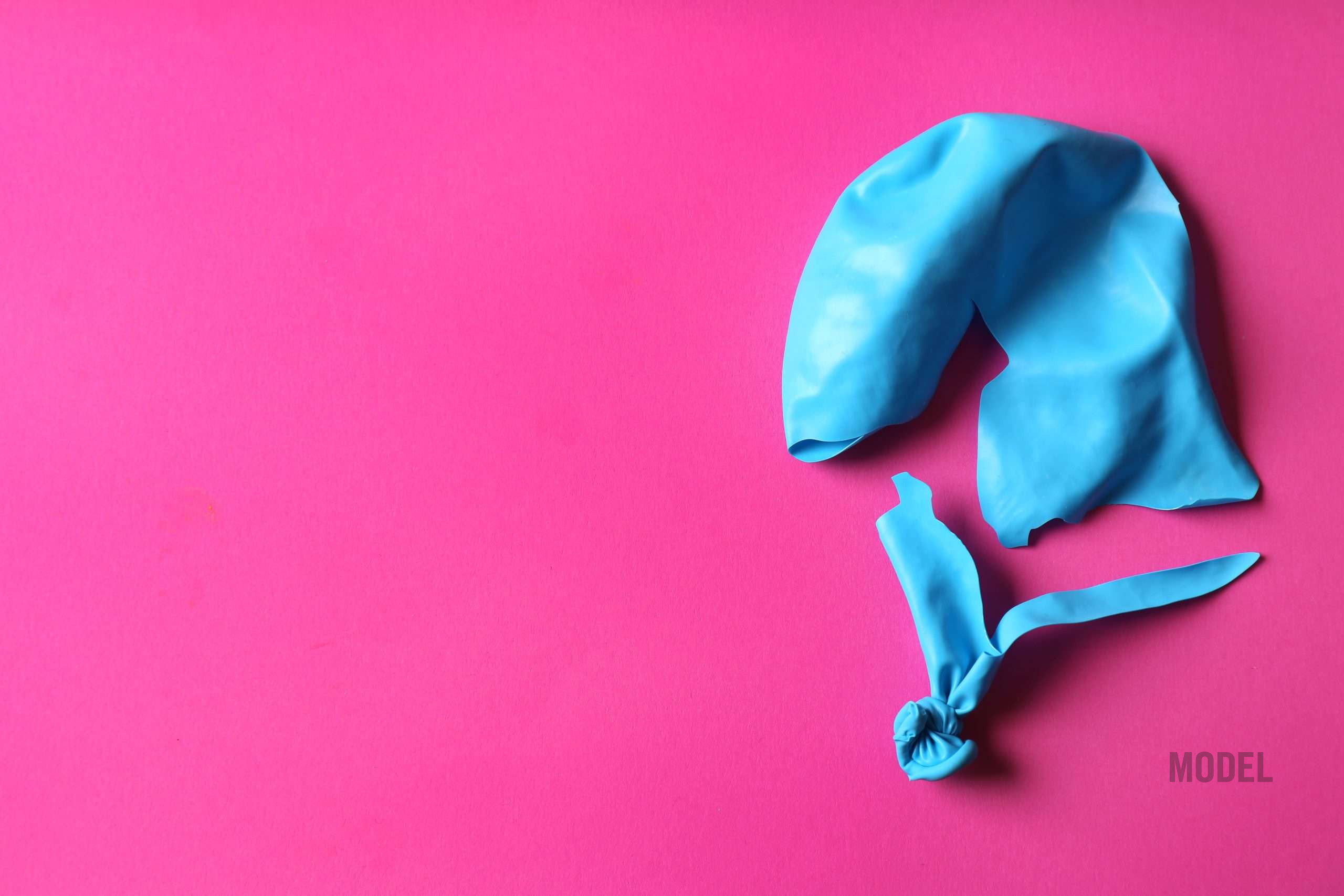Popped balloon representing breast implant downsizing, breast implant revision, and concerns about deflation after implant removal